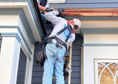 gutter installers working on blue house with copper gutters in haddonfield nj