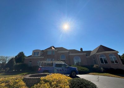 sun shines over a brick house with seamless gutters in shamong nj with van's rain gutters truck parked out front south jersey